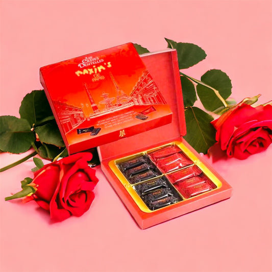 A box of Maxim's dark and milk chocolate lace crepes with individual wrappers visible. The box is open, revealing the crepes and the elegant packaging.